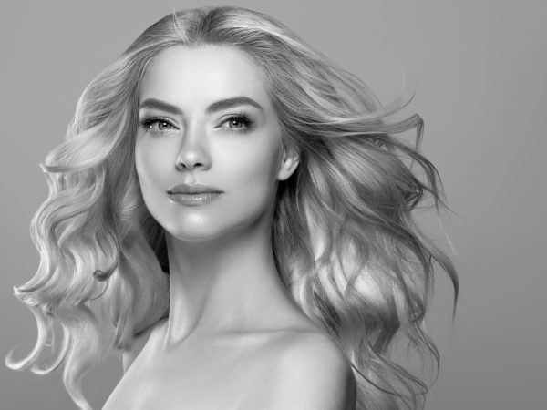 Blonde face woman curly hair beauty face natural makeup . Studio shot. Monochrome gray black and white.